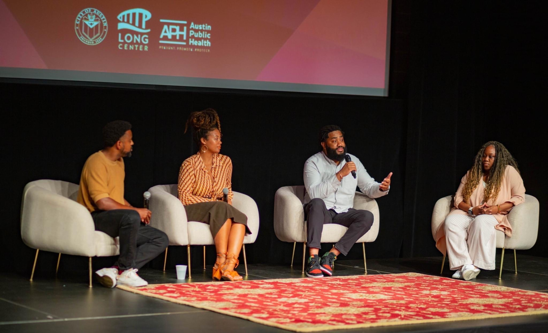 Jerold McDonald speaking with a microphone during a panel conversation on stage at the Long Center in Austin
