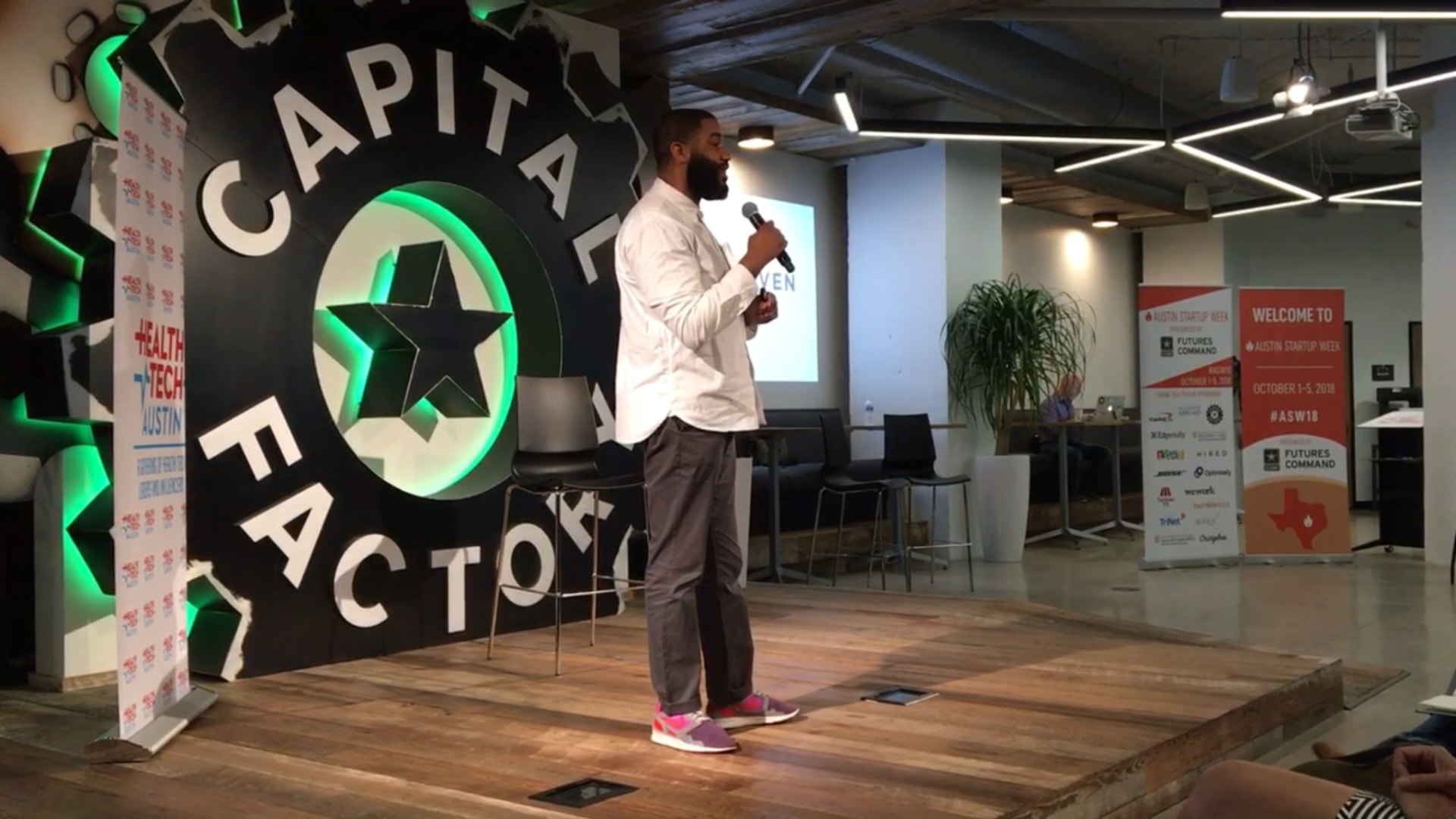 Jerold McDonald speaking with a microphone on stage at Capital Factory in Austin during Austin Startup Week